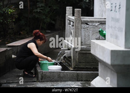 Eine in der Nähe ansässige holt das Wasser aus dem 600 Jahre alten Yujing alten Brunnen im Downtown Bereich, in Guiyang City, im Südwesten Chinas Guizhou provinc