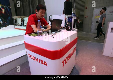 ---- Ein chinesischer Mitarbeiter ist auf dem Stand der Toshiba während des 14 China Digital Entertainment Expo gesehen, auch als ChinaJoy 2016 in Shanghai bekannt, Stockfoto