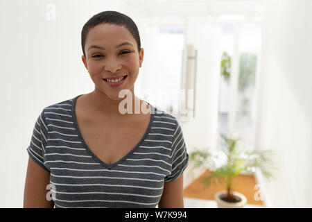 Glückliche junge Frau lächelnd in die Kamera zu Hause Stockfoto