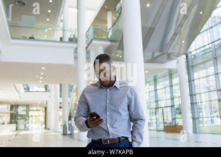 Geschäftsmann mit Smartphone in der modernen Lobby Stockfoto