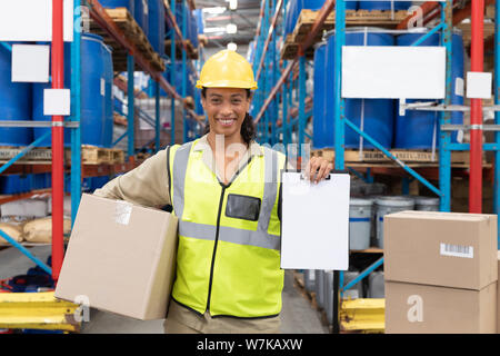 Arbeiterin mit Karton und Zwischenablage im Lager Stockfoto