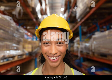 Glückliche Arbeitnehmerin an Kamera suchen im Lager Stockfoto