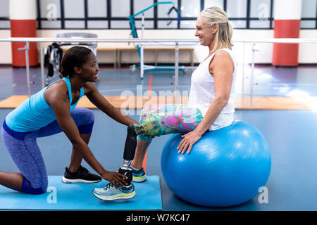 Trainer unterstützen behinderte ältere Frau im Sport Center Stockfoto