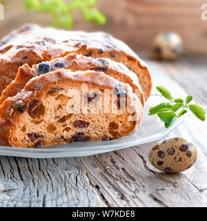 Osterbrot Osterbrot (in deutscher Sprache), quadratische Komposition. Close-up auf traditionellen fruty Brot auf rustikalem Holz mit frischen Blätter und Wachteleier. Tradition Stockfoto