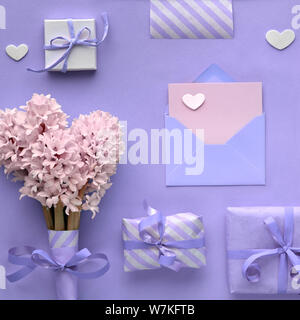 Lila Frühling Hintergrund mit rosa Hyazinthe Blumen, verpackte Geschenkboxen und dekorative Herzen, copy-Platz auf leere Karte im Umschlag, Quadrat compo Stockfoto