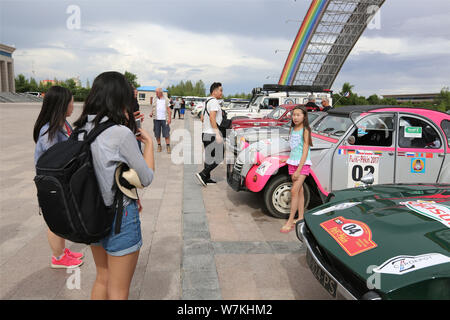 Anwohner posieren für Fotos mit Oldtimern in Erenhot City, North China Autonome Region Innere Mongolei, den 8. August 2017. Oldtimer arriv Stockfoto