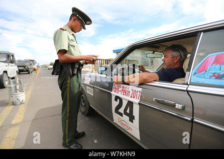 Ein chinesischer Polizist prüft einen Oldtimer, wie er in der Stadt ankommt, Erenhot Norden Chinas Innere Mongolei Autonome Region, 8. August 2017. Vintage Stockfoto