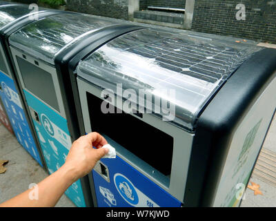 Ein Fußgänger, wirft seinen Müll in eine intelligente solar Mülltonne auf einer Straße in Nanjing, Provinz Jiangsu im Osten Chinas, den 9. August 2017. Intelli Stockfoto