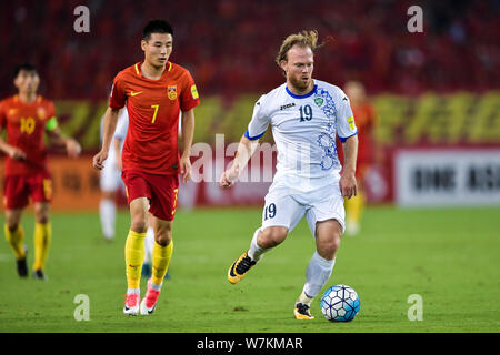 Vitaliy Denisov, rechts, Usbekistans kickt den Ball einen Pass gegen Wu Lei von China in Ihrer Gruppe eine Runde 9 Spiel während der FIFA WM 2018 zu machen Stockfoto