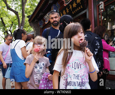 Ausländer genießen Sie Eis mit der Form der Blume an der Nanluoguxiang Gasse in Dongcheng District, Beijing, China, 28. August 2017. Eis Stockfoto