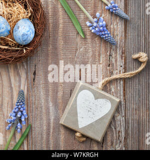 Ostern Hintergrund mit Eiern, blaue Hyazinthen Blumen und hölzerne Herz, Ansicht von oben auf der rustikalen, mit Holz, Quadrat Zusammensetzung Stockfoto