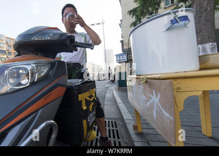 ---- Ein Radler trinkt das Wasser von den Chinesischen ältere Frau Cui Chuanmian an Passanten angeboten - von in Nanjing, Provinz Jiangsu, China 2. Stockfoto