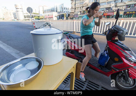 ---- Ein Radler trinkt das Wasser von den Chinesischen ältere Frau Cui Chuanmian an Passanten angeboten - von in Nanjing, Provinz Jiangsu, China 2. Stockfoto