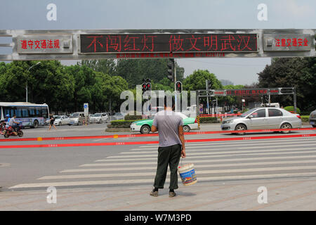 Ein Fußgänger wartet auf ein rotes Licht vor der geschlossenen automatische Seil System auf einer Straßenkreuzung in Wuhan City grün, der Central China Hube Stockfoto