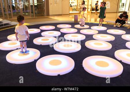 Besucher Schritt auf ein Brüllen pads Interaktiv - Licht Projekt' 'Pool'', Skulptur Künstler Jen Lewin erstellt, an Jing An Kerry Centre in Sh Stockfoto