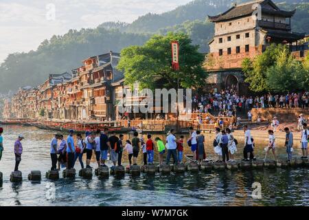 Touristen gehen Sie zu Fuß steht die Tuo Tuojiang River (Fluss) in der Alten Stadt Fenghuang Scenic Area in Fenghuang Grafschaft zu Kreuz, Xiangxi Tujia und Stockfoto