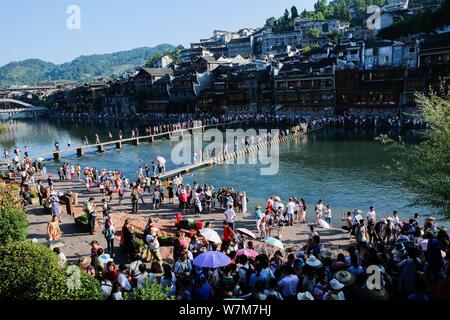 Touristen gehen Sie zu Fuß steht die Tuo Tuojiang River (Fluss) in der Alten Stadt Fenghuang Scenic Area in Fenghuang Grafschaft zu Kreuz, Xiangxi Tujia und Stockfoto