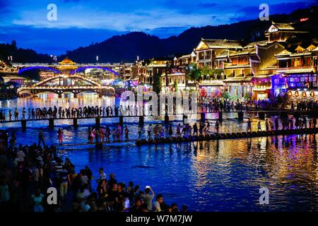 Touristen gehen Sie zu Fuß steht die Tuo Tuojiang River (Fluss) in der Alten Stadt Fenghuang landschaftlich reizvollen Gegend in der Nacht Kreuz in Fenghuang County, Xiangxi T Stockfoto