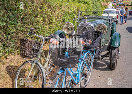 Zwei alte Fahrräder, neben einem Schreibwaren Oldtimer im ruhigen Dorf Heydon in Norfolk geparkt Stockfoto