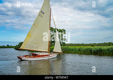 Ein einsamer Seemann auf einem traditionellen Segelboot Heften entlang des Flusses Bure in den Norfolk Broads Stockfoto