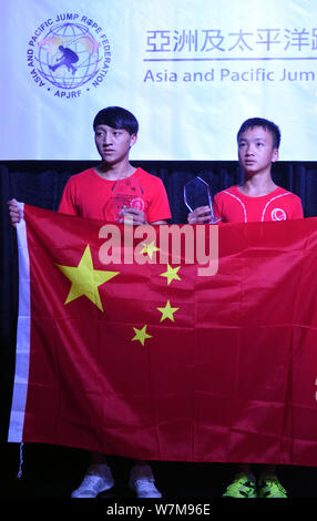 Cen Xiaolin, ein 13-jähriger Junge aus dem Süden Chinas Guangdong, rechts, stellt seine Trophäe und die Flagge der Volksrepublik China afte Stockfoto