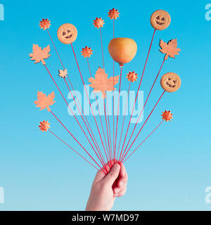 Herbst Luftballons, kreative noch Leben in Blau und Orange mit Kürbis, Cookies und Blätter im Herbst an Fäden in der Hand, square Zusammensetzung Stockfoto