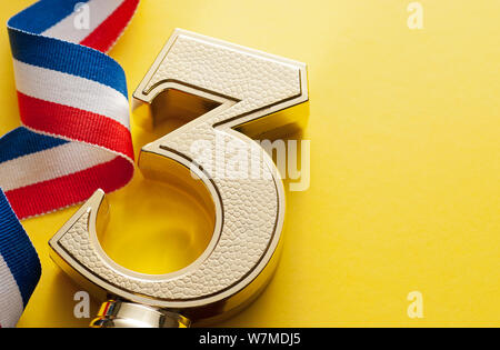 3. platzierten Läufer oben championship Trophäe in Form eines strukturierten Gold dimensionale Nummer drei mit Twirled Band auf einem gelben Hintergrund mit kopieren Stockfoto