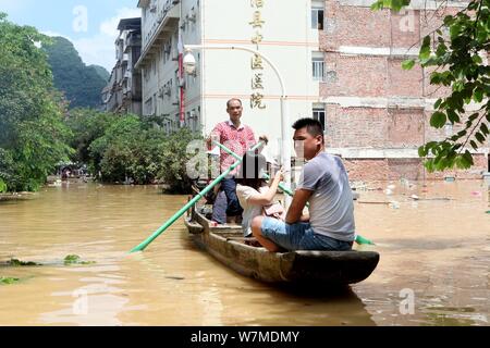 Anwohner fahren Sie mit dem Boot auf einer überfluteten Straße durch starken Regen in Rongshui Miao autonomen County, South China Guangxi Zhuang autonomen Regio verursacht Stockfoto