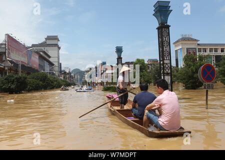 Anwohner fahren Sie mit dem Boot auf einer überfluteten Straße durch starken Regen in Rongshui Miao autonomen County, South China Guangxi Zhuang autonomen Regio verursacht Stockfoto