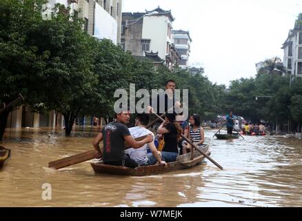 Anwohner fahren Sie mit dem Boot auf einer überfluteten Straße durch starken Regen in Rongshui Miao autonomen County, South China Guangxi Zhuang autonomen Regio verursacht Stockfoto