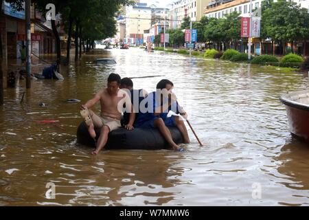 Die anwohner nehmen ein aufblasbares Schlauchboot auf einer überfluteten Straße durch starken Regen in der yongfu Grafschaft, der Stadt Guilin, South China Guangxi Zhuang Autom. Stockfoto
