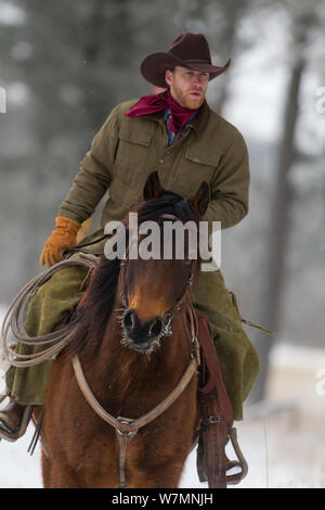 Cowboy reiten durch Schnee, Wyoming, USA, Februar 2012, Modell freigegeben Stockfoto