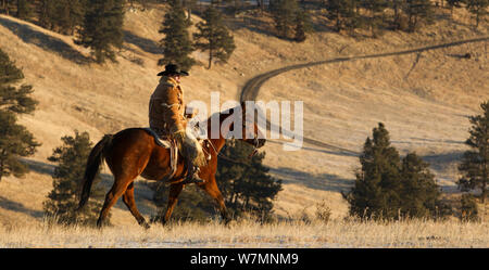 Cowboy reiten, mit dicken Schaffellmantel, Wyoming, USA, Februar 2012, Modell freigegeben Stockfoto