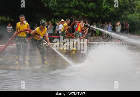 Soldaten Schlauch Wasser weg Schlamm zu löschen, nachdem ein Hochwasser im Riverside Park in Liucheng County von Liuzhou City, South China Guangxi Zhuang autonomen Regi Stockfoto