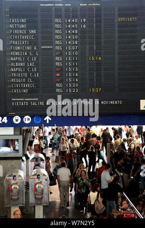 Menschenmassen passieren durch ein Brett mit Abfahrtszeiten zur Stazione Termini in Rom Stockfoto