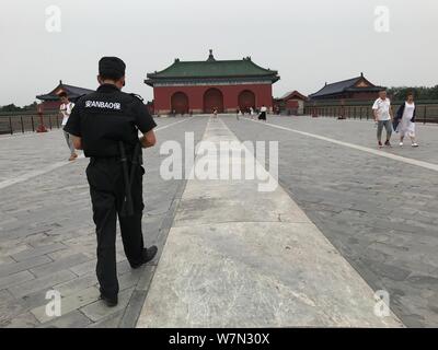 Ein chinesischer Sicherheitsmann Spaziergänge entlang der Danbi Brücke mit Besuchern liegen auf im Tempel des Himmels Park Schmerz auf einen heißen Gaming-Sommer Tag zu entlasten, Stockfoto