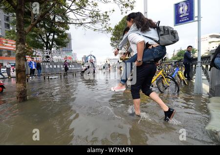 Ein chinesischer Mann seine Freundin, die Spaziergänge auf einer überfluteten Straße von Unwettern in Kunming City verursacht, im Südwesten der chinesischen Provinz Yunnan, 20. Juli Stockfoto