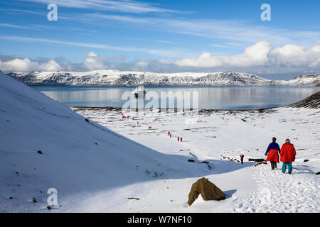 Touristen zu Fuß rund um den Kratersee von Deception Island, mit einem Kreuzfahrtschiff in den Hintergrund, South Shetland Inseln, Antarktis. Februar 2007. Stockfoto