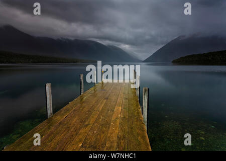 Lake Rotoiti und Bootsanleger im Moody Abendlicht, regen Wolken fegen über die umliegenden Berge. Blick nach Süden, in Richtung der Travers River Valley, Nelson Lakes National Park, St. Arnaud, Tasman Region, South Island, Neuseeland. Oktober, 2006. Stockfoto