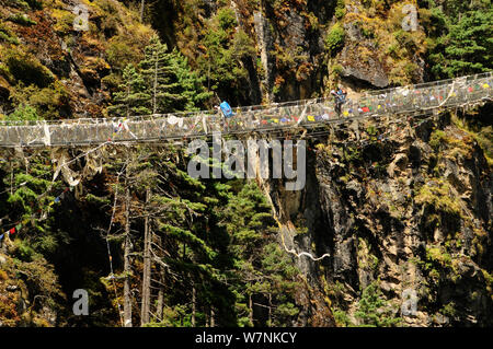 Menschen wandern über Hängebrücke über den Dudh Kosi River, Sagarmatha National Park (Weltkulturerbe der UNESCO). Khumbu/Everest Region, Nepal, Himalaya, Oktober 2011 Stockfoto