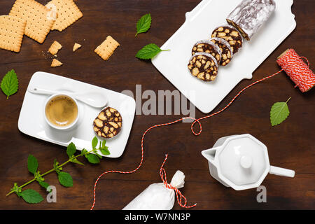 Leckere Schokolade salami Cookies mit Tasse Espresso auf rustikalen Holzmöbeln Hintergrund. Flach. Stockfoto