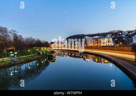 Deutschland, Stadt Saarbrücken Nacht Verkehr und Gebäude in Saar Wasser in magischer Atmosphäre widerspiegelt Stockfoto