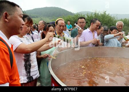 Touristen sammeln für einen Geschmack von frischen Pflaumen Wein in ein zwei Meter Durchmesser Topf während der ersten moked Pflaume Tourismus Festival' in Dachuan Stadt, Südwesten Stockfoto