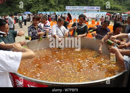 Touristen sammeln für einen Geschmack von frischen Pflaumen Wein in ein zwei Meter Durchmesser Topf während der ersten moked Pflaume Tourismus Festival' in Dachuan Stadt, Südwesten Stockfoto