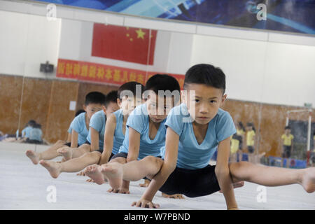 Junge chinesische Jungs verbiegen ihre Körper mit ihren Händen auf dem Boden zu halten, Gymnastik auf dem Boden der Gymnastik an einem Gy zu üben, zu üben Stockfoto