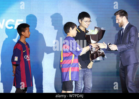 Argentinischen Stürmer Lionel Messi vom FC Barcelona, rechts, erhält Blumen aus einer jungen chinesischen Ventilator während einer Pressekonferenz für die Messi Erfahrung Stockfoto