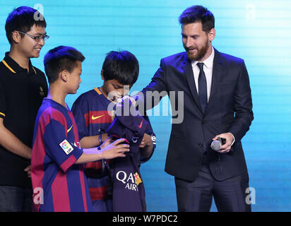 Argentinischen Stürmer Lionel Messi vom FC Barcelona, rechts, erhält Blumen aus einer jungen chinesischen Ventilator während einer Pressekonferenz für die Messi Erfahrung Stockfoto