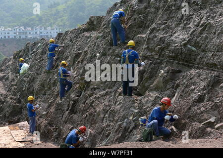 Chinesische Arbeiter auszugraben Dinosaurier Fossilien in einer Wand 150 Meter lang, 2 Meter tief und 8 Meter hoch, an der Ausgrabungsstätte in Laojun vi konzentriert Stockfoto