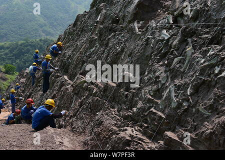 Chinesische Arbeiter auszugraben Dinosaurier Fossilien in einer Wand 150 Meter lang, 2 Meter tief und 8 Meter hoch, an der Ausgrabungsstätte in Laojun vi konzentriert Stockfoto