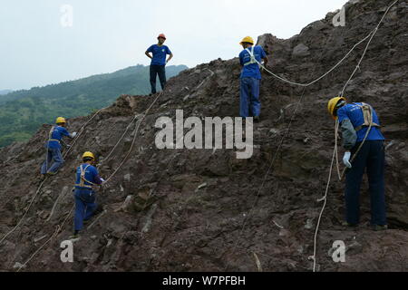 Chinesische Arbeiter auszugraben Dinosaurier Fossilien in einer Wand 150 Meter lang, 2 Meter tief und 8 Meter hoch, an der Ausgrabungsstätte in Laojun vi konzentriert Stockfoto